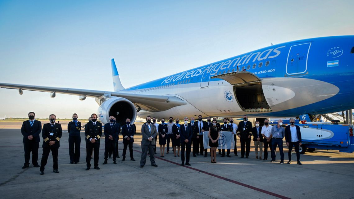 Crew members and authorities pose next to an Aerolineas Argentinas airplane before its departure to bring 300,000 doses of the Sputnik V vaccine against Covid-19 from Moscow, in Buenos Aires on December 22, 2020. 