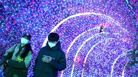 Las personas usan sus teléfonos móviles mientras caminan en un centro comercial en Beijing.