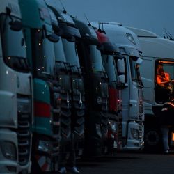 Los conductores de camiones de carga y vehículos pesados están iluminados por las luces dentro de sus cabinas mientras están estacionados en una parada de camiones en la M20 que conduce a Dover, cerca de Folkestone en Kent, sureste de Inglaterra, después de que Francia cerró sus fronteras a la carga acompañada que llega desde el Reino Unido debido a la rápida propagación de una nueva cepa de coronavirus. | Foto:Justin Tallis / AFP
