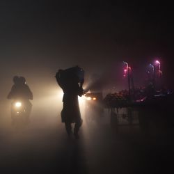 La gente camina por una carretera en medio del smog y la niebla en Lahore. | Foto:Arif Ali / AFP