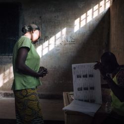 Los votantes esperan mientras los funcionarios de la comisión electoral verifican la lista de votantes en el colegio electoral de la escuela secundaria Barthélemy Boganda en el primer distrito de Bangui, República Centroafricana (RCA), durante las elecciones presidenciales y legislativas del país. | Foto:Añlexis Huguet / AFP