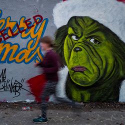 Una pintura mural del artista de graffiti Eme Freethinker presenta una imagen del personaje Grinch del autor estadounidense Dr. Seuss con un sello de  | Foto:John Macdougall / AFP