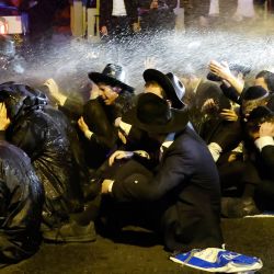 La policía israelí utiliza un cañón de agua para dispersar a los judíos ultraortodoxos que bloquean una carretera en la ciudad de Bnei Brak, en el centro de Israel, durante una manifestación contra la detención de un miembro de su comunidad que se negó a realizar el servicio militar. | Foto:Jack Guez / AFP