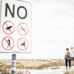 Turistas caminan por el paseo que limita la playa principal vacía en Langebaan. - El presidente sudafricano Cyril Ramaphosa anunció el 28 de diciembre de 2020 nuevas medidas de bloqueo para limitar la propagación del COVID-19. Se han cerrado playas en áreas identificadas como puntos críticos de COVID-19. | Foto:Marco Longari / AFP