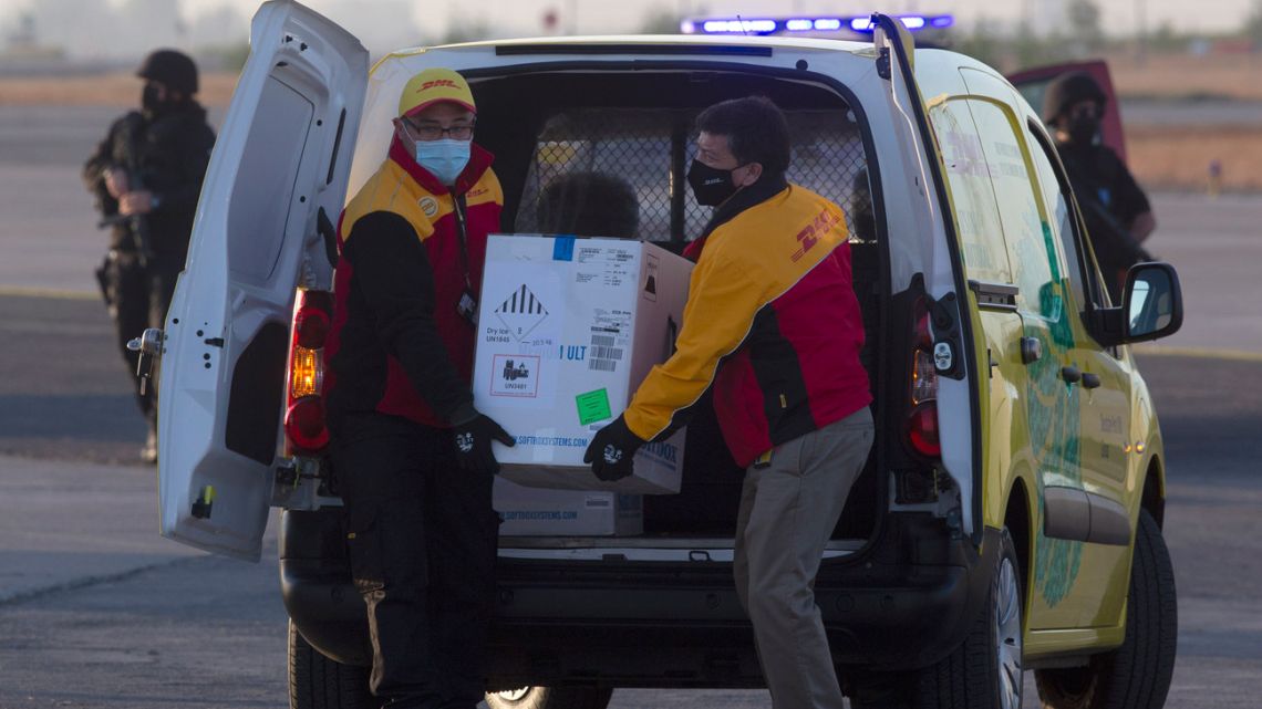 Workers carry a box containing the Pfizer-BioNTech Covid-19 coronavirus vaccine to a helicopter for distribution at the international airport in Santiago on December 24, 2020. 