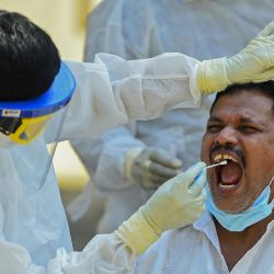 Un trabajador médico que usa equipo de protección toma una muestra de hisopo de un residente para realizar la prueba del coronavirus Covid-19 en Colombo. | Foto:Ishara S. Kodikara / AFP