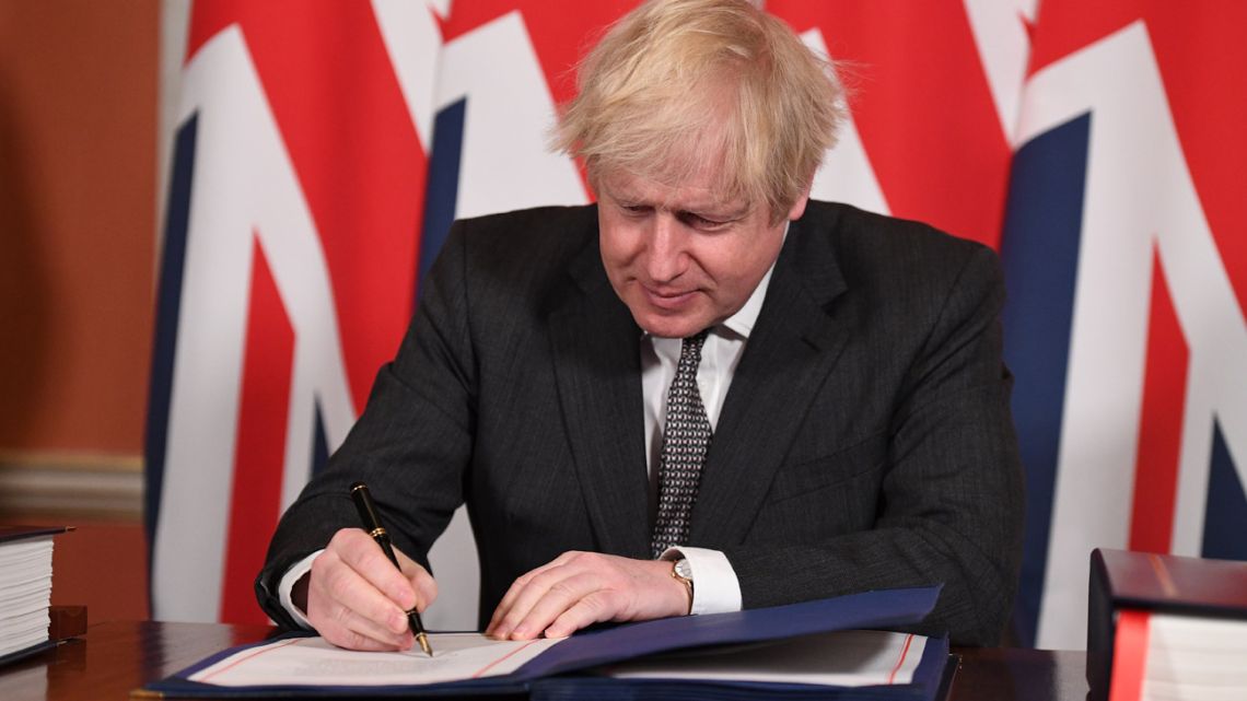 Britain's Prime Minister Boris Johnson signs the Trade and Cooperation Agreement between the UK and the EU, the Brexit trade deal, at 10 Downing Street in central London on December 30, 2020. 