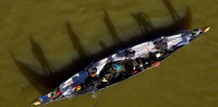 Hombres colocan una red en un barco de pesca en el río Bassac en Phnom Penh.