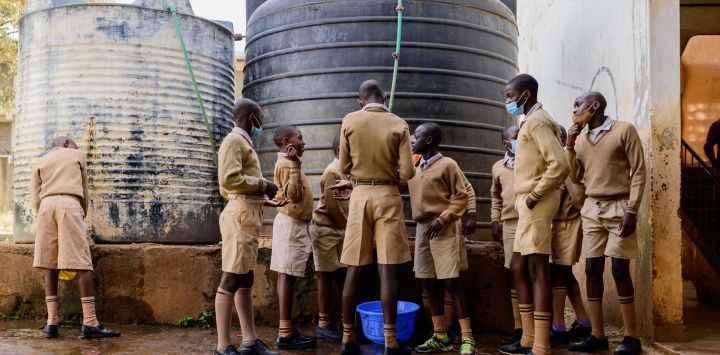 Los estudiantes de la escuela primaria Ayany llenan un recipiente con agua para limpiar el aula antes de la clase en la mañana del día oficial de reapertura de las escuelas públicas, en el barrio marginal de Kibera, Kenia, cuando los estudiantes regresan a la escuela después de nueve meses.