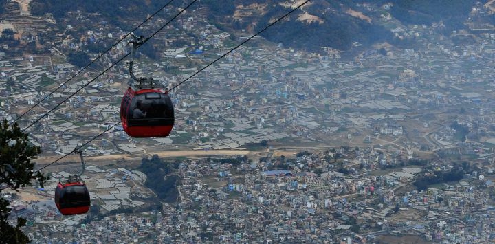 Los pasajeros viajan en un teleférico en la cima de la colina Chandagiri en medio de condiciones de niebla tóxica en Katmandú.