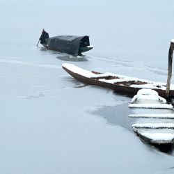 Un barquero usa un remo para romper la capa de hielo de la parte congelada del lago Dal después de las fuertes nevadas en Srinagar. | Foto:Tauseef Mustafa / AFP