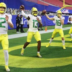Los mariscales de campo Tyler Shough, Anthony Brown y Bradley Yaffe de los Oregon Ducks calientan antes del PlayStation Fiesta Bowl contra los Iowa State Cyclones en State Farm Stadium en Glendale, Arizona. | Foto:Christian Petersen / Getty Images / AFP