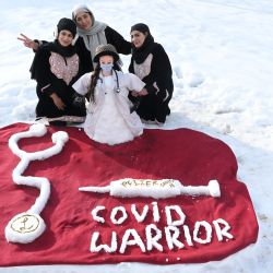 Mujeres posan con una escultura de nieve de un médico, una vacuna y un estetoscopio en honor a los trabajadores de la salud y su lucha contra el coronavirus Covid-19, luego de una fuerte nevada en Srinagar. | Foto:Tauseef Mustafa / AFP