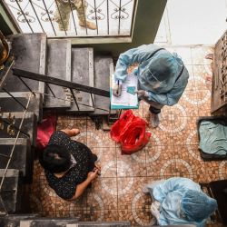 Un trabajador de salud peruano se prepara para realizar una prueba de COVID-19 a una mujer en su casa del distrito El Agustino en Lima. | Foto:Ernesto Benavides / AFP