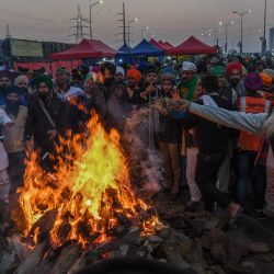 Los agricultores que protestan celebran el festival de Lohri alrededor de una hoguera, mientras continúan su protesta a lo largo de una carretera bloqueada contra las recientes reformas agrícolas del gobierno central, en la frontera estatal de Gazipur Delhi-Uttar Pradesh, en Ghaziabad. | Foto:Prakash Singh / AFP