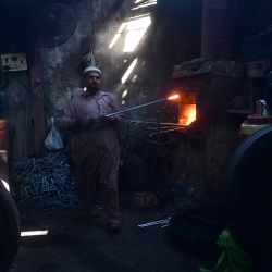 Un trabajador trabaja en una pequeña fábrica de hierro en Karachi. | Foto:Asif Hassan / AFP