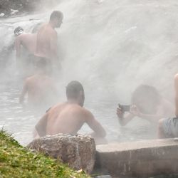 Los migrantes utilizan una salida termal de una fuente termal natural cercana para bañarse en el suburbio occidental de Ilidza en Sarajevo. | Foto:Elvis Barukcic / AFP