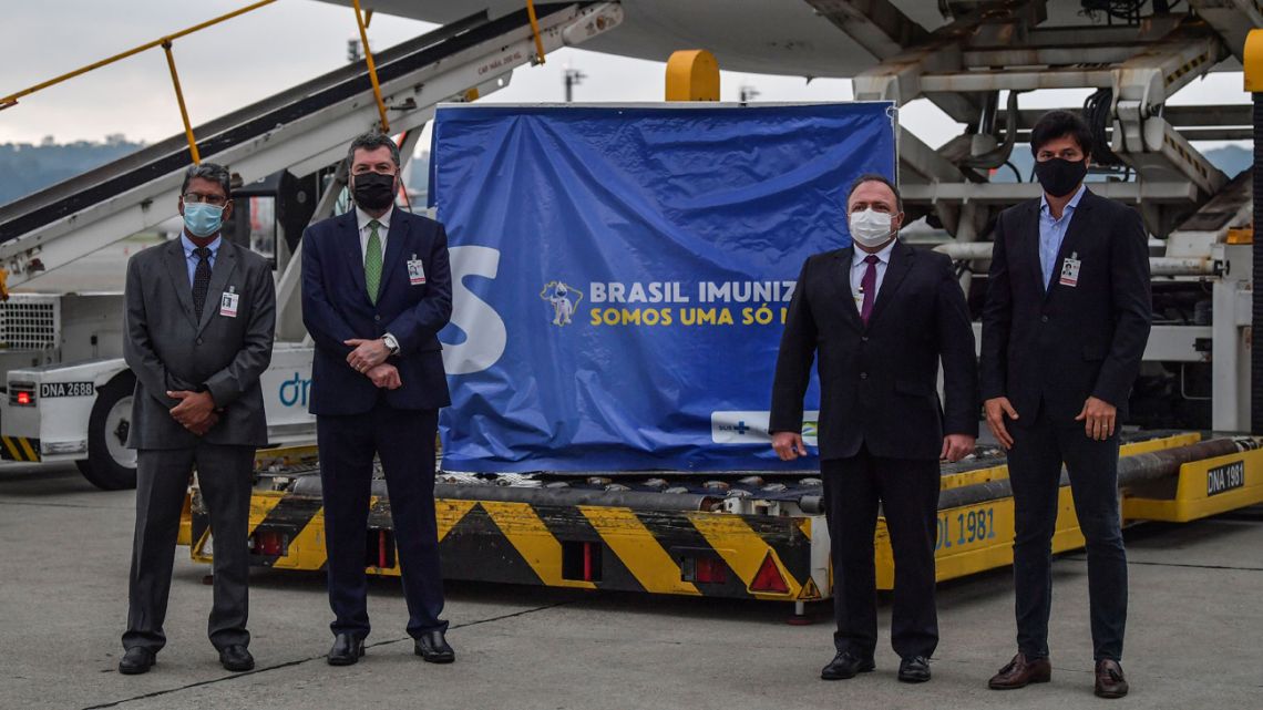 Brazilian Health Minister Eduardo Pazuello (second right), Foreign Minister Ernesto Araujo (second left), Communications Minister Fabio Faria (right) and the Ambassador of India in Brazil Suresh Reddy (left), pose for photos next to a container carrying doses of the Oxford/AstraZeneca vaccine that arrived from India at the Guarulhos International Airport, near Sao Paulo, Brazil, on January 22, 2021. Brazil received Friday a first lot with two million doses of the Oxford/AstraZeneca vaccine developed by the Serum Institute of India. 
