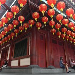 La gente se sienta fuera del Templo de la Reliquia del Diente de Buda decorado con linternas para celebrar el próximo Año Nuevo Lunar en el área de Chinatown de Singapur. | Foto:Roslan Rahman / AFP