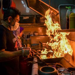 Un hombre con mascarilla cocina un plato en un restaurante de Kuala Lumpur. | Foto:Mohd Rasfan / AFP