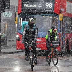 Los ciclistas viajan frente a un autobús de Oxford Street mientras cae la nieve en Londres. | Foto:Justin Tallis / AFP
