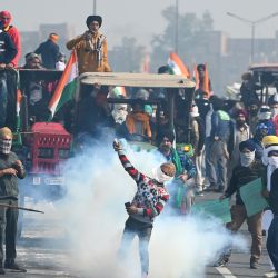 Un agricultor arroja un proyectil de gas lacrimógeno disparado por la policía para dispersarlos durante una manifestación de tractores mientras los agricultores continúan manifestándose contra las recientes reformas agrícolas del gobierno central en Nueva Delhi. | Foto:Sajjad Hussain / AFP