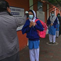Un miembro del personal verifica la temperatura corporal de una estudiante a su llegada a una escuela en Lahore, cuando el gobierno reabrió los institutos educativos en la fase 2 del grado 1 al 8 después de permanecer cerrados como medida preventiva en medio del Covid-19. pandemia de coronavirus. | Foto: Arif Ali / AFP