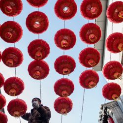 Un trabajador instala linternas chinas tradicionales a lo largo de un callejón antes del Año Nuevo Lunar del Buey en Beijing. | Foto:Noel Celis / AFP