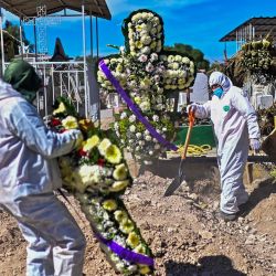 Sepultureros colocan flores en la tumba de una víctima del Covid-19 en el Panteón Municipal de Ecatepec, Estado de México, México. | Foto:Pedro Pardo / AFP