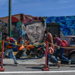 La gente camina junto a un mural que representa al difunto presidente Hugo Chávez, en el centro de Caracas. | Foto:Federico Parra / AFP