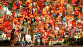 La gente camina bajo las decoraciones festivas para el próximo Año Nuevo Lunar frente a un centro comercial en Bangkok.