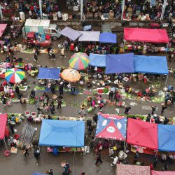 Esta vista aérea muestra a personas comprando alimentos en un mercado de agricultores en Jishou, en la provincia de Hunan, en el centro de China. | Foto:STR / AFP