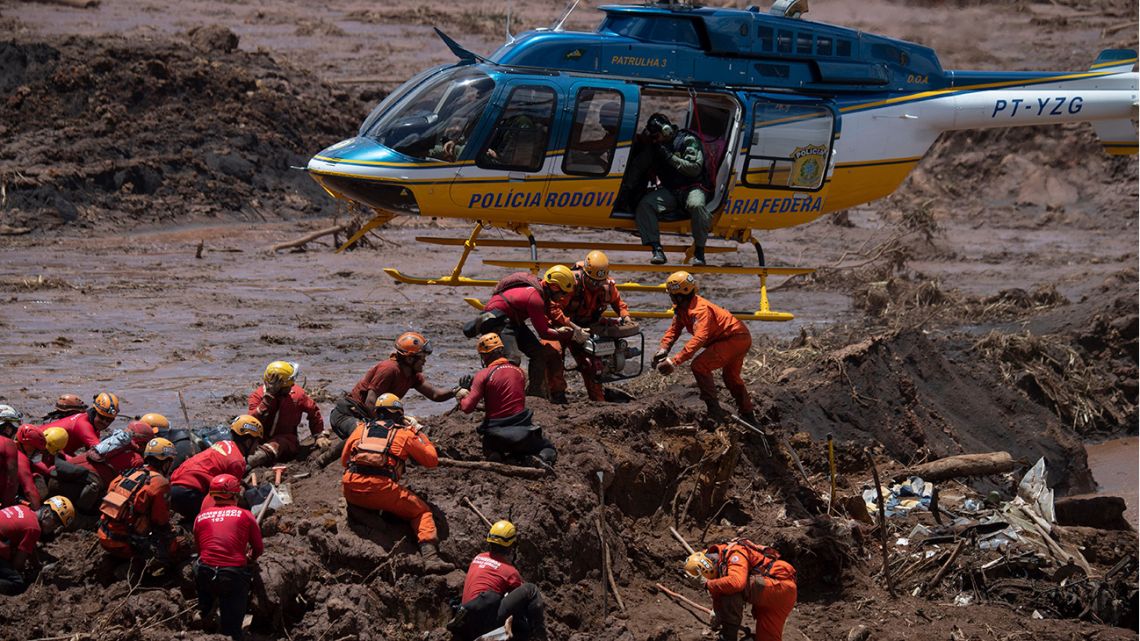 Firefighters receive equipment to open a vehicle found in the mud as they search for victims of Friday's dam collapse at an iron-ore mine belonging to Brazil's giant mining company Vale near the town of Brumadinho.