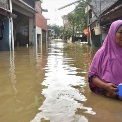 Una mujer camina por una calle inundada en Bekasi, en las afueras de Yakarta. | Foto:Rezas / AFP