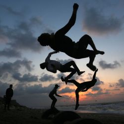 Jóvenes palestinos demuestran sus habilidades de parkour durante la puesta de sol en la playa de Deir Al-Balah. | Foto:Ashraf Amra / APA Imágenes a través de ZUMA Wire / DPA