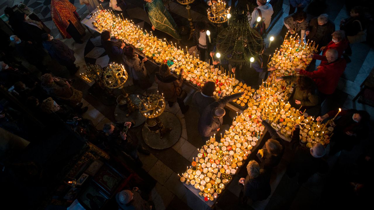Los creyentes rezan alrededor de una plataforma en forma de cruz cubierta con velas unidas a tarros de miel durante una ceremonia que marca el día de San Haralampi, santo patrón ortodoxo de los apicultores, en la Iglesia de la Santísima Virgen en Blagoevgrad, Bulgaria oriental. | Foto:Nikolay Doychinov / AFP