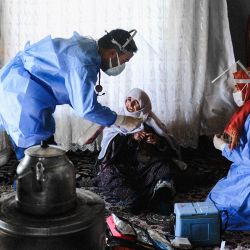 Berfo Arsakay, de 101 años, se prepara para recibir una vacuna del doctor Akay Kaya y la enfermera Yildiz Ayten del equipo de vacunación del hospital público de Bahcesaray, en la aldea. de Guneyyamac en el este de Turquía, como parte de una expedición para vacunar a los residentes de 65 años o más con la vacuna CoronaVac Covid-19 de Sinovac. | Foto:Bulent Kilic / AFP