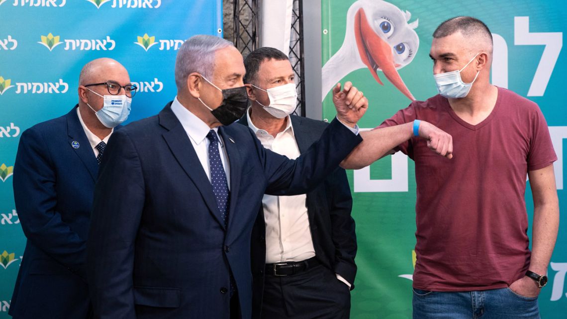 Israeli Prime Minister Netanyahu gives a elbow bump to the 4,000,000th person to be vaccinated at Leumit Health Care Services vaccination facility in Jerusalem on February 16, 2021. 