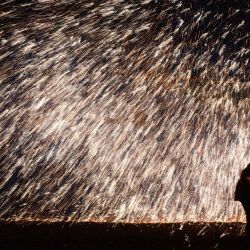 Esta foto muestra a un artista arrojando hierro fundido para crear fuegos artificiales durante una actuación tradicional china  | Foto:STR / AFP
