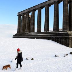 Una persona camina con un perro más allá del Monumento Nacional en Calton Hill, cubierto de nieve en el centro de Edimburgo. - El clima frío que azota el norte de Europa trae nieve y hielo. | Foto:Andy Buchanan / AFP