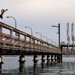 Los jóvenes saltan al agua del Mar Rojo desde un muelle petrolero abandonado en la ciudad portuaria de Eilat, en el sur de Israel. | Foto:Menahem Kahana / AFP)