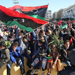 Los libios ondean banderas nacionales mientras se reúnen en la Plaza de los Mártires de la capital, Trípoli, para celebrar el décimo aniversario de la revolución de 2011. - El levantamiento derrocó al antiguo gobernante Moamer Kadhafi, poniendo fin a una dictadura de larga duración, pero arrojando al país en un década de anarquía violenta. | Foto:Mahmud Turkia / AFP
