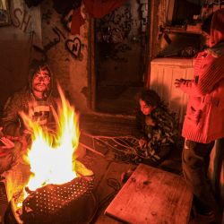 Los miembros de una familia palestina se reúnen alrededor de una fogata en su casa en un vecindario empobrecido durante una tormenta en la ciudad de Gaza. | Foto:MAHMUD HAMS / AFP