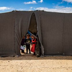Los niños se asoman a través de la apertura de una tienda de campaña en el campamento de al-Hol, dirigido por los kurdos, que alberga a presuntos familiares de combatientes del grupo Estado Islámico (EI), en la gobernación de Hasakeh, en el noreste de Siria. | Foto:Delil Souleiman / AFP