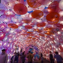 Muestra a personas que pasan junto a una exhibición de paraguas decorados con luces para el próximo Festival de los Faroles en una calle comercial en Hangzhou, en la provincia de Zhejiang, en el este de China. | Foto:AFP