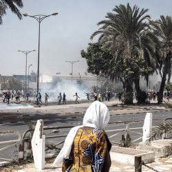 Una mujer camina frente a los partidarios que protestaban del líder de la oposición de Senegal, OusmaneSonko, cuando estalló una protesta violenta en Dakar | Foto:AFP