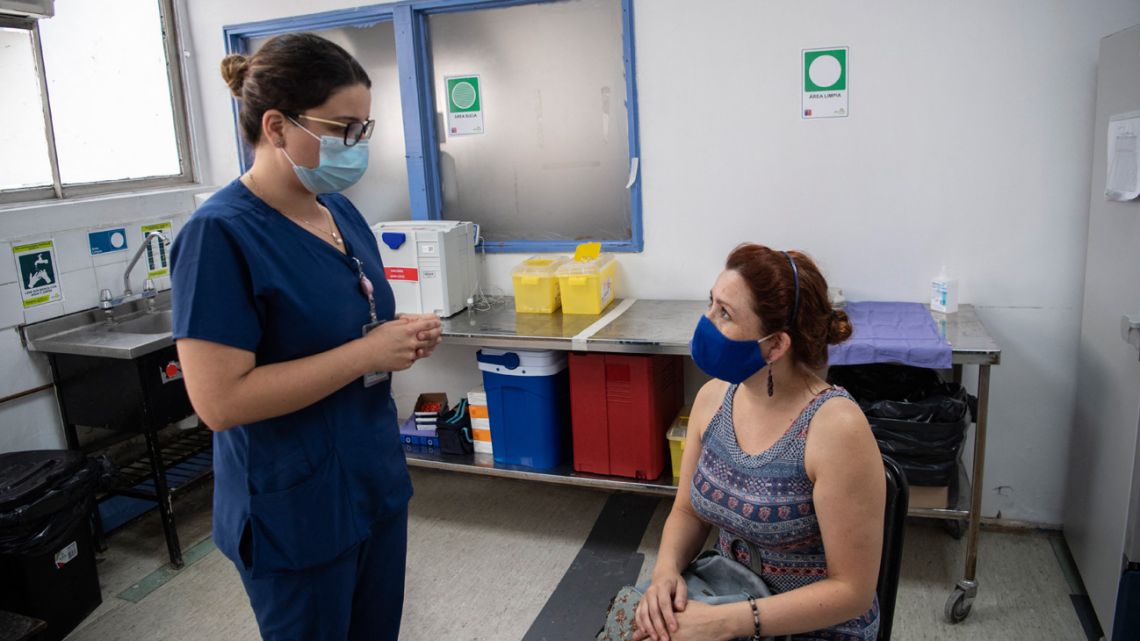 Chilean nurse Maria Paz Herreros, 32, who was the first to inoculate a patient against Covid-19 in Chile, speaks with a patient about the Chinese Sinovac vaccine, at the Metropolitan Hospital in Santiago, on February 26, 2021. 