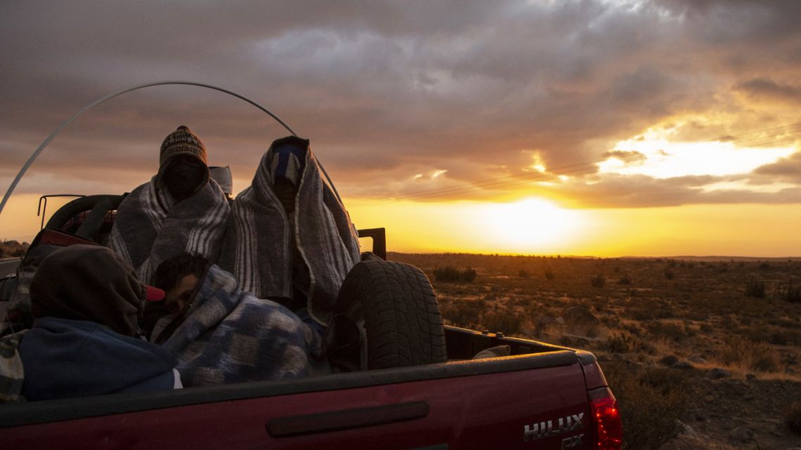 Venezuelan migrant Rubi Alexander G. (right) and friends travel in the back of a truck along Route 15, after crossing from Bolivia, in Huara, Chile, on February 17, 2021. Crossing the highlands of the border between Bolivia and Chile on foot is the hardest part of the journey Venezuelan migrants go through on their way to Iquique or Santiago.