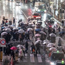 La gente cruza una calle en el área de Shibuya durante una lluvia en Tokio cuando los funcionarios extendieron el estado de emergencia por el coronavirus Covid-19 por quince días. | Foto:AFP