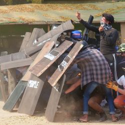 Un manifestante hace un gesto hacia las fuerzas de seguridad mientras se refugian detrás de escudos durante una manifestación contra el golpe militar junto a la Pagoda Shwezigon en Nyaung-U, cerca del sitio del patrimonio mundial de la UNESCO, Bagan. | Foto:STR / AFP